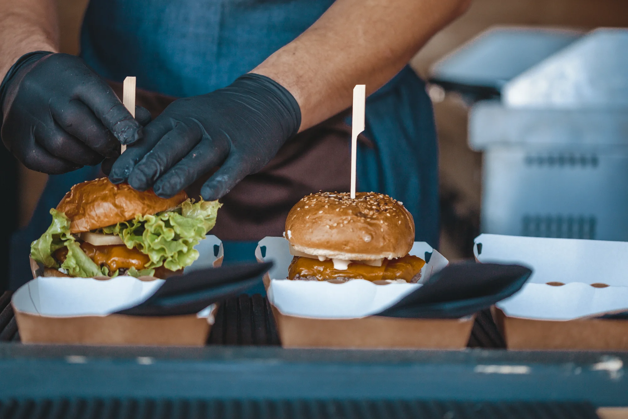 Chef preparing burgers with gloves on.