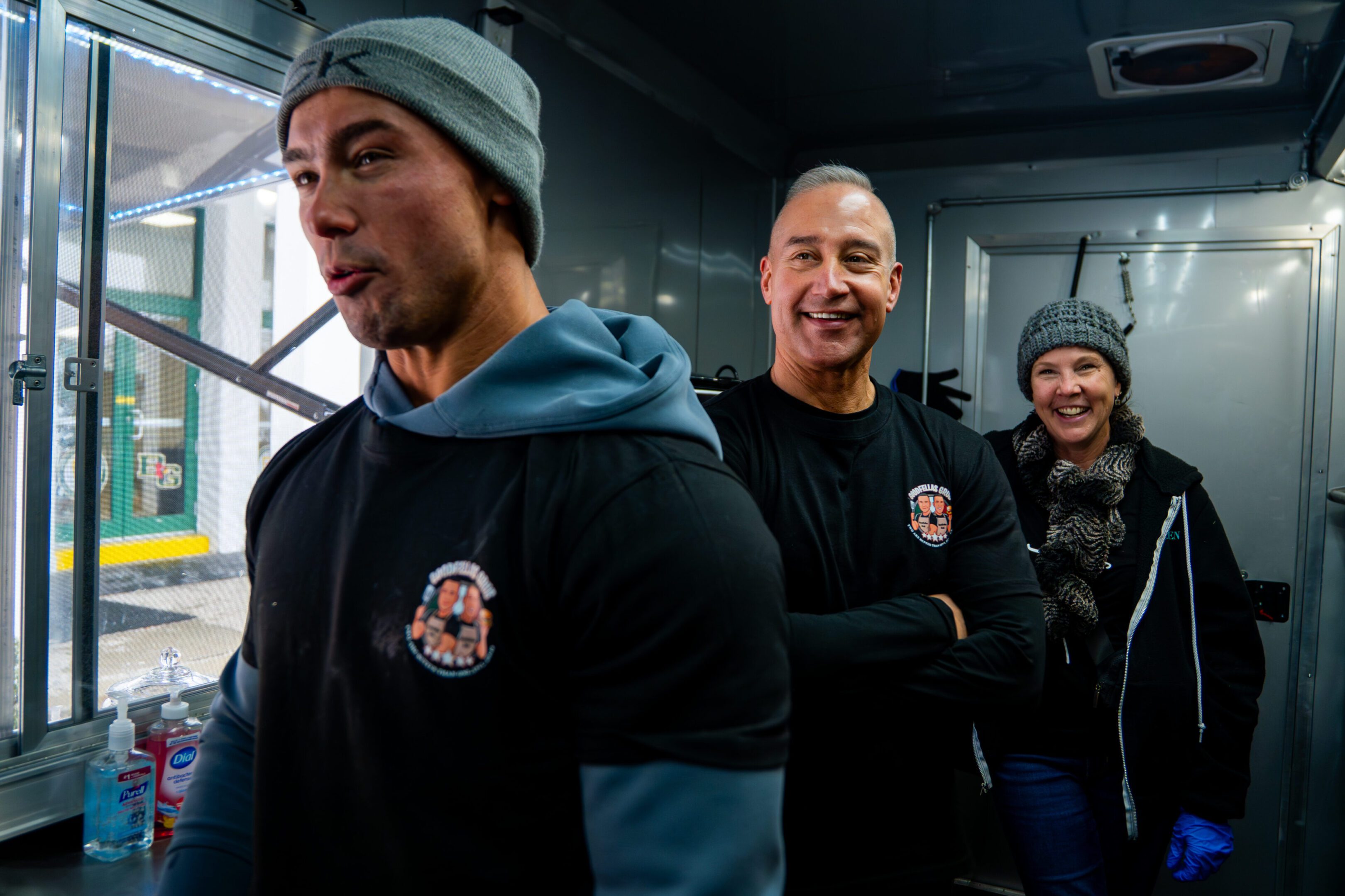Three firefighters smiling and posing in their station.