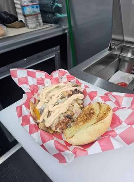 A delicious sandwich with grilled meat and creamy sauce on a bun.