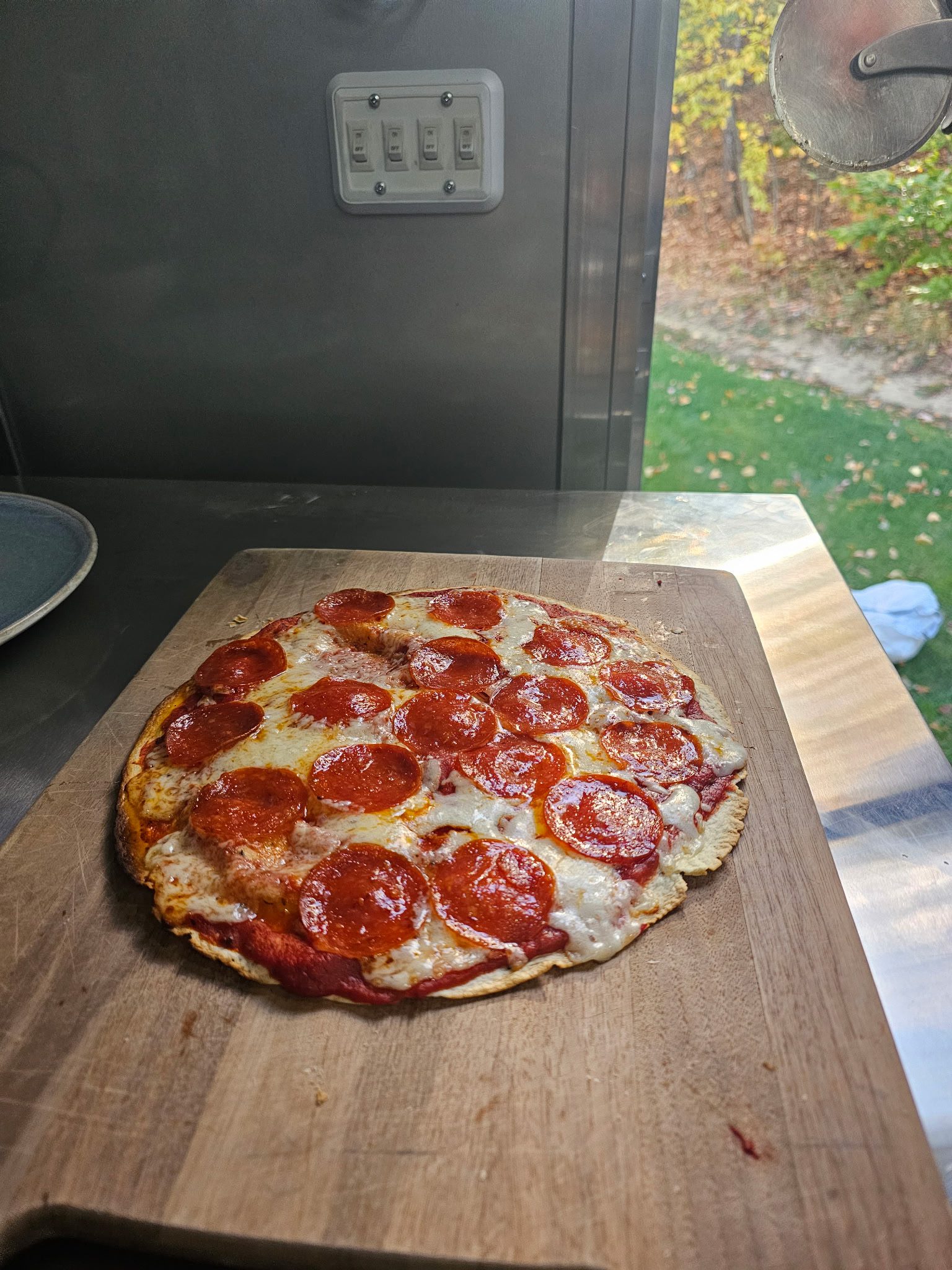A freshly baked pepperoni pizza on a wooden board.