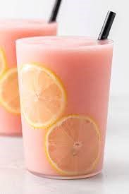 A pink smoothie with lemon slices in a glass.